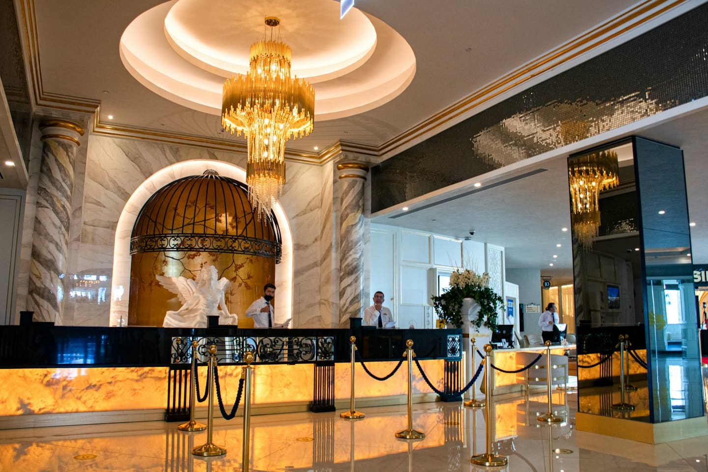 Due uomini dietro un banco reception di un hotel con accenti dorati.