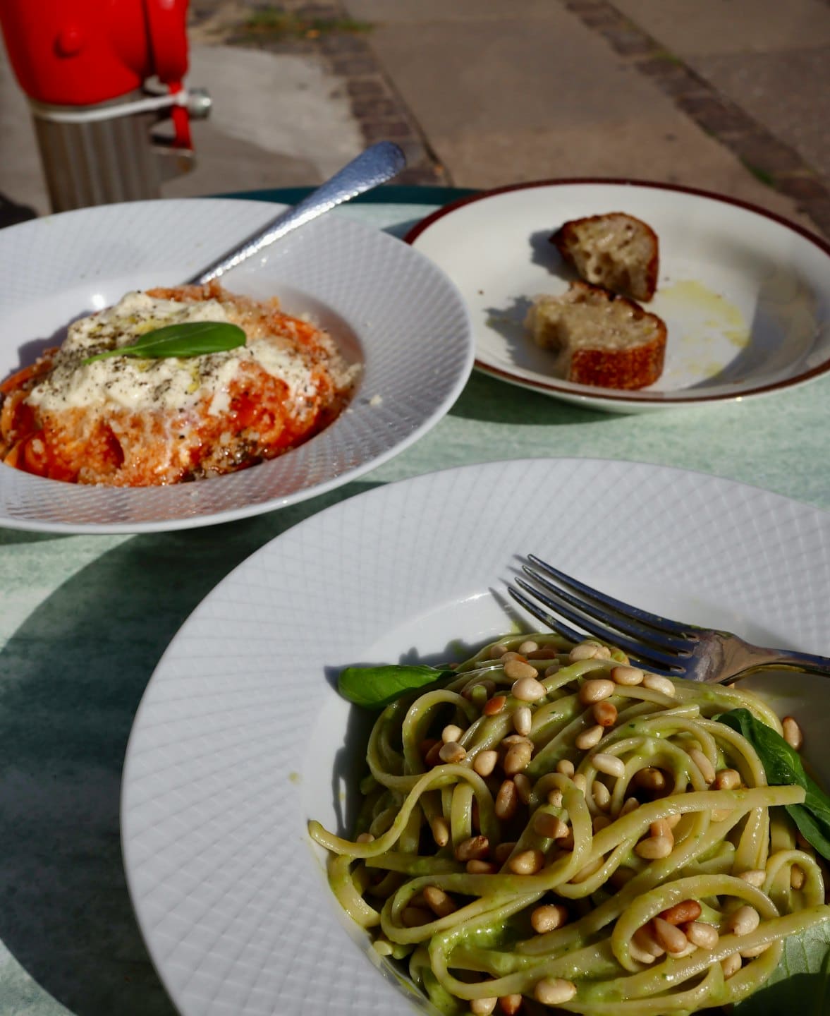 Due piatti di pasta e pane su un tavolo all'aperto.