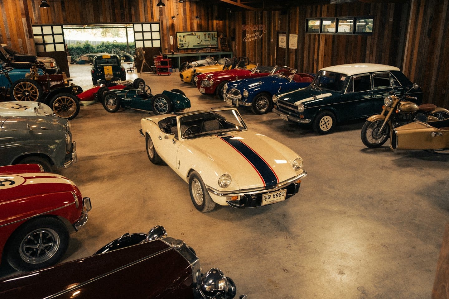 Auto d'epoca e una moto parcheggiate all'interno di un garage in legno.