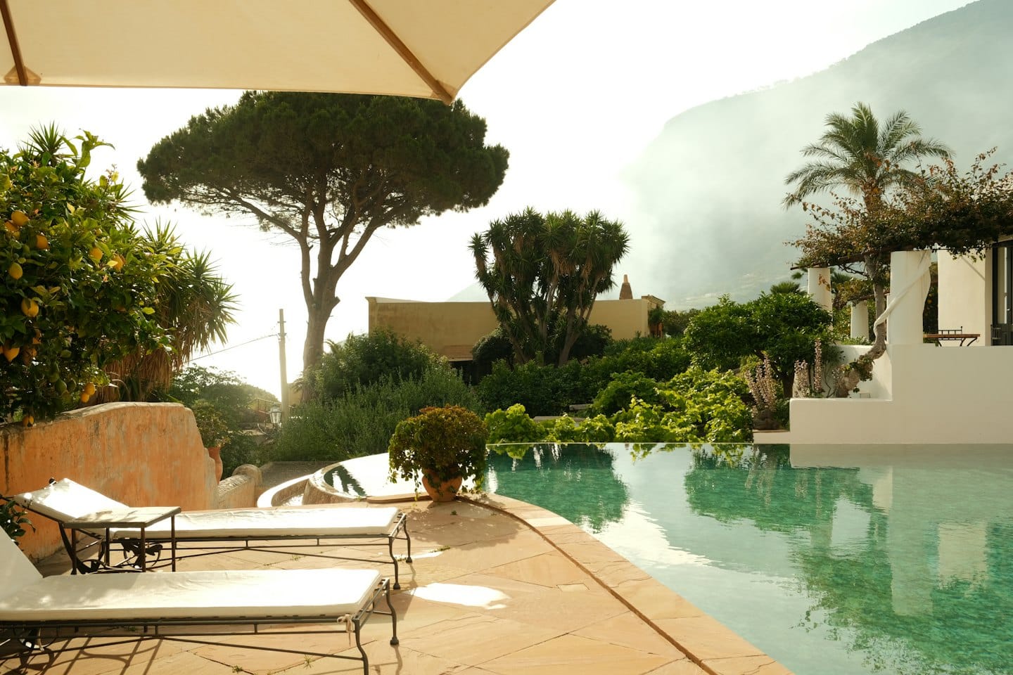 Lettini prendisole accanto a una piscina curva su una terrazza.